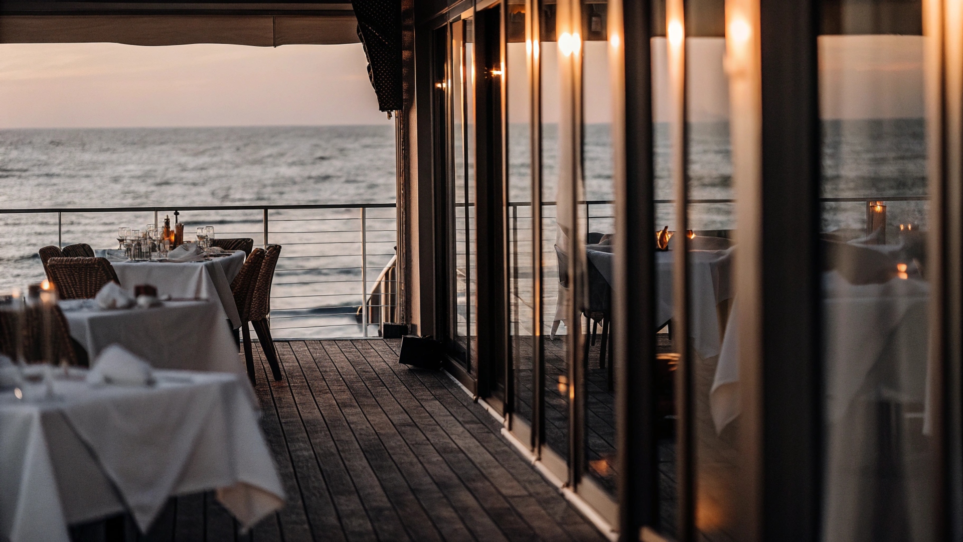 Terrazza del ristorante La Mariposa con tavoli apparecchiati e vista sul mare di Ostia al tramonto